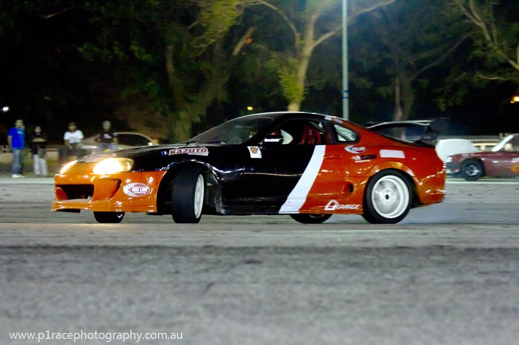 Speed City drift night - Orange and black Toyota Supra - Kazuto Garage - Front three-quarter pan 2 (light 77)